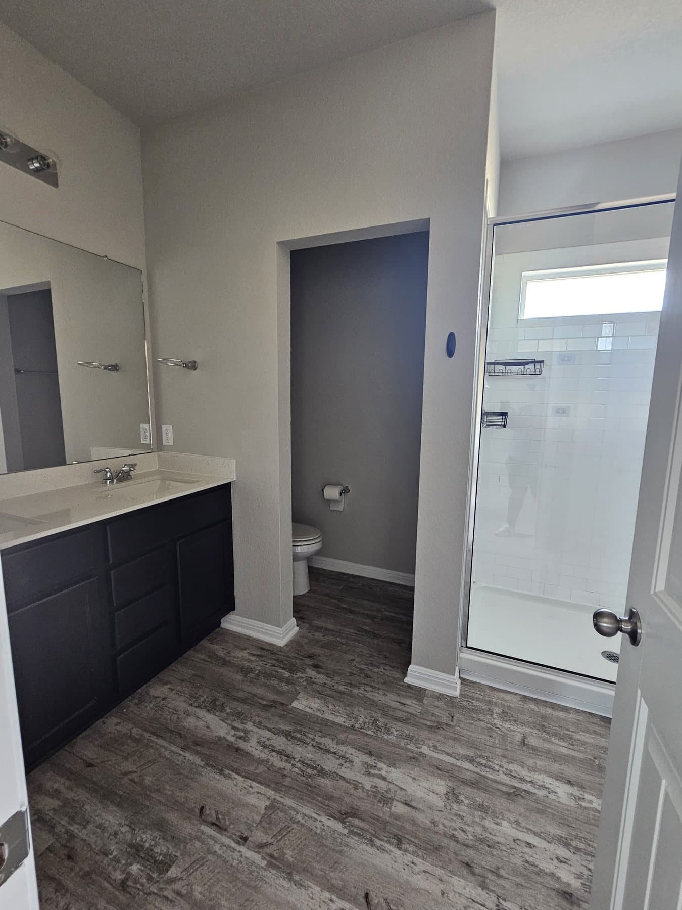 Freshly painted bathroom with dark vanity, large mirror and walk-in shower