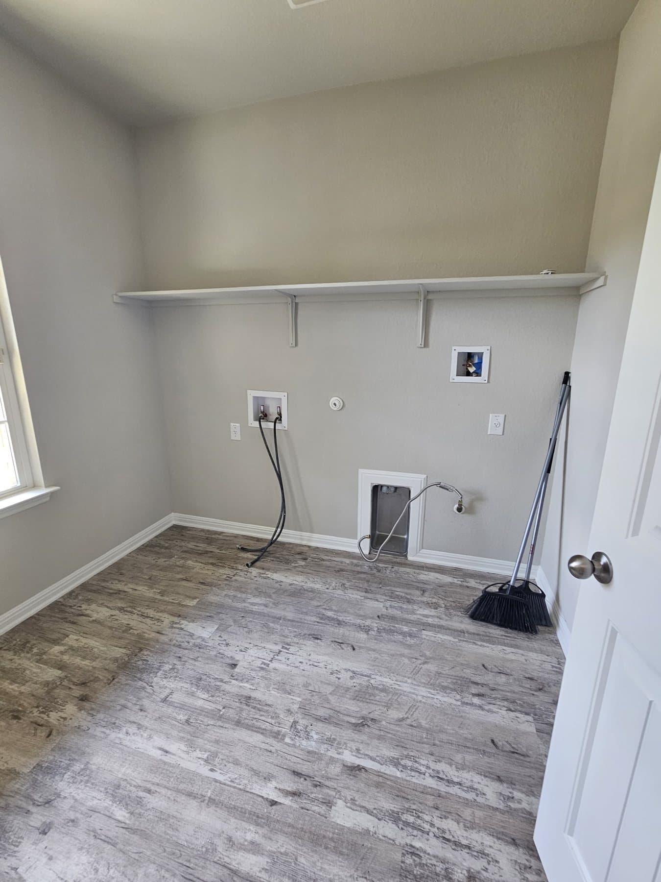Freshly painted laundry room with hanging rail and utility connections