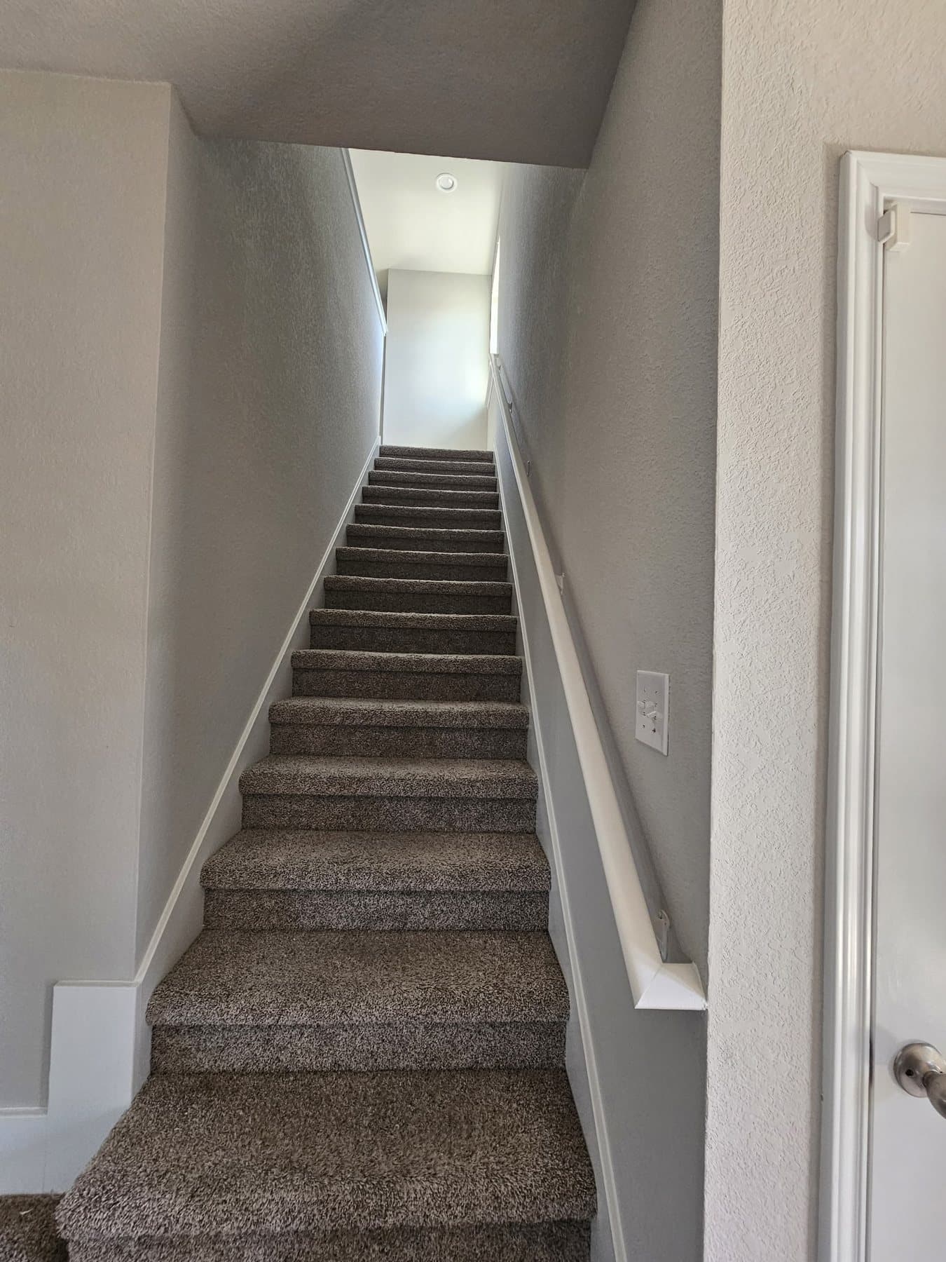 Freshly painted two-storey stairwell with white handrail and trim