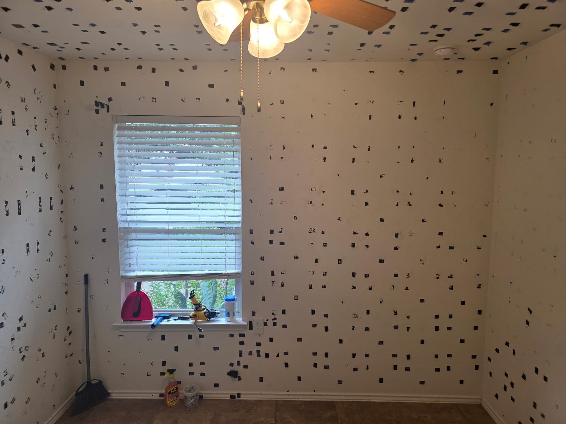 Second view of a bedroom with adhesive residue across the walls and ceiling before prep