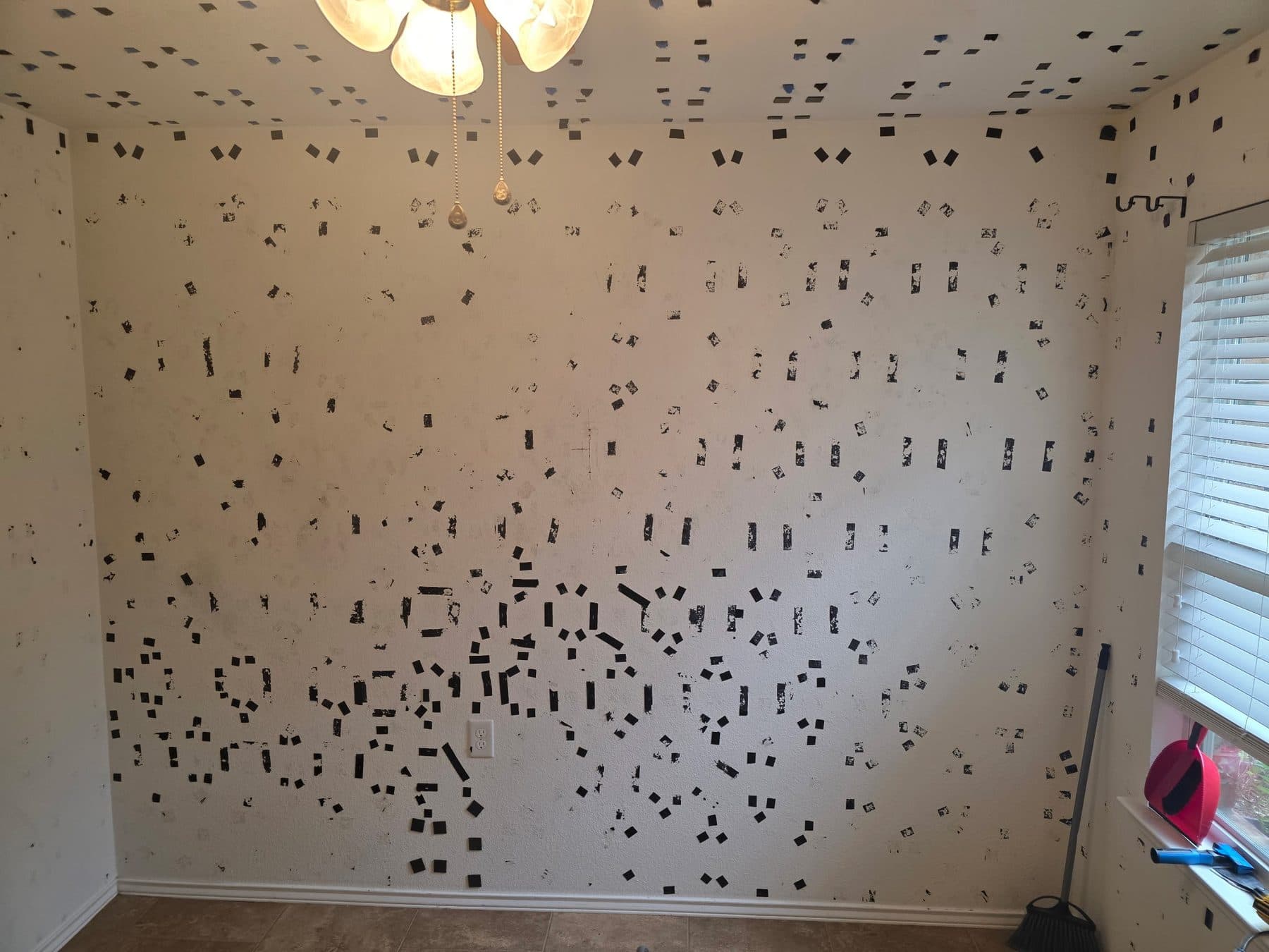 Bedroom wall and ceiling covered in dark adhesive residue before repainting