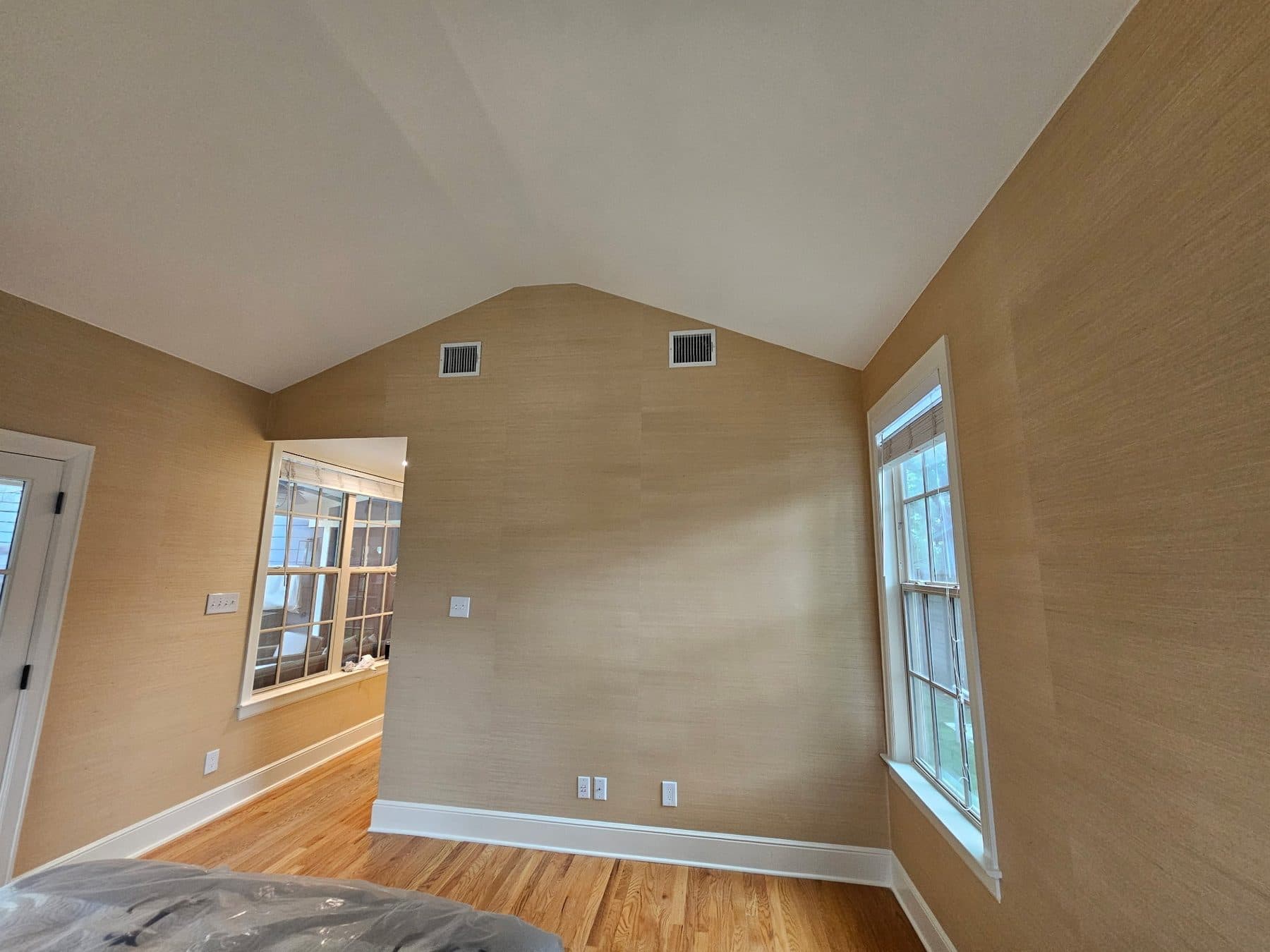 Finished bedroom with warm painted walls, white trim and hardwood floor