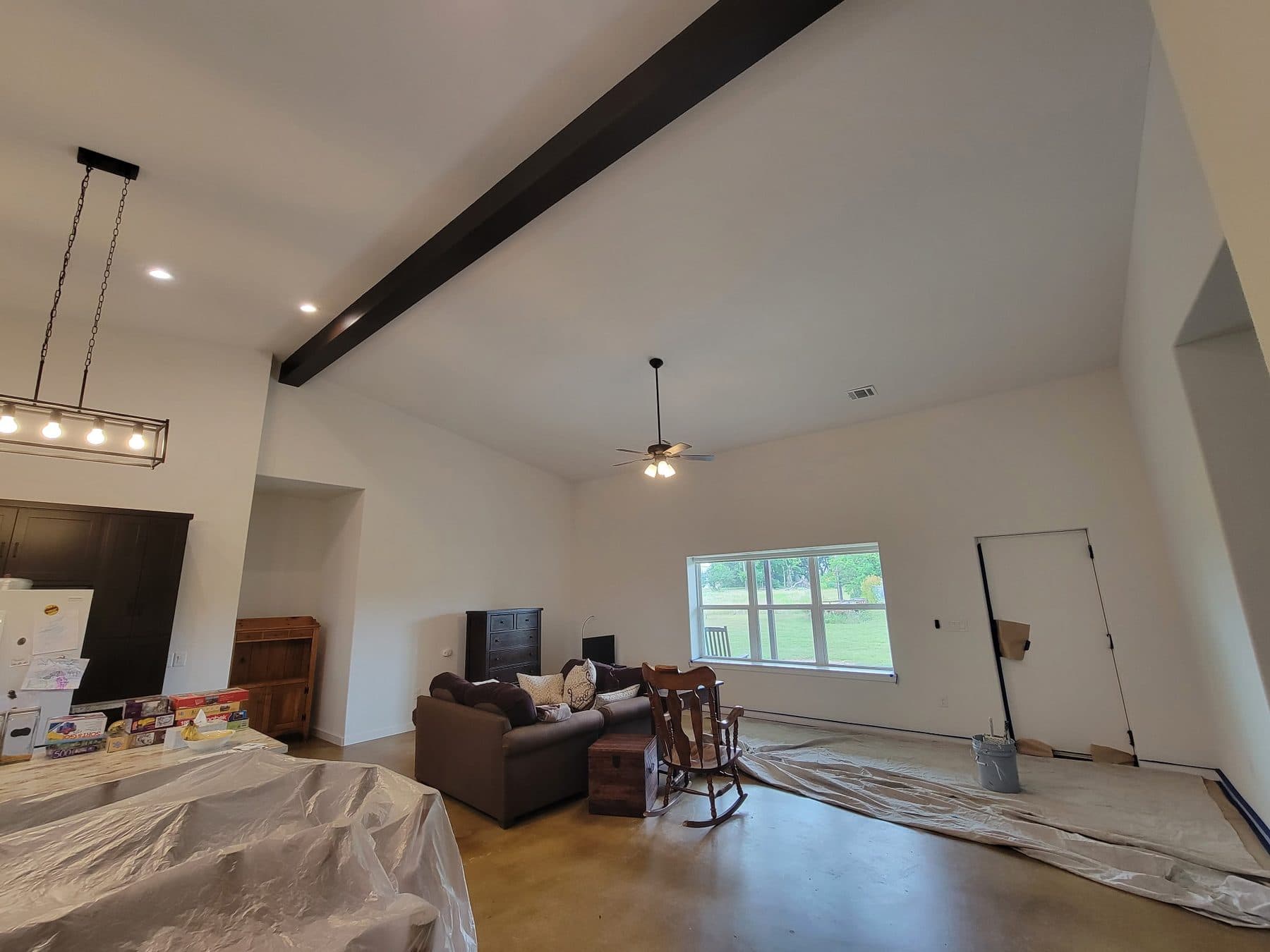 Open plan living room with furniture moved to the centre and covered in protective sheeting