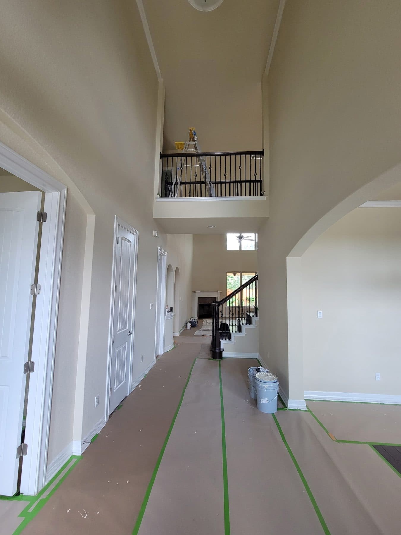 Upstairs hallway with green tape and full-length floor protection during a repaint