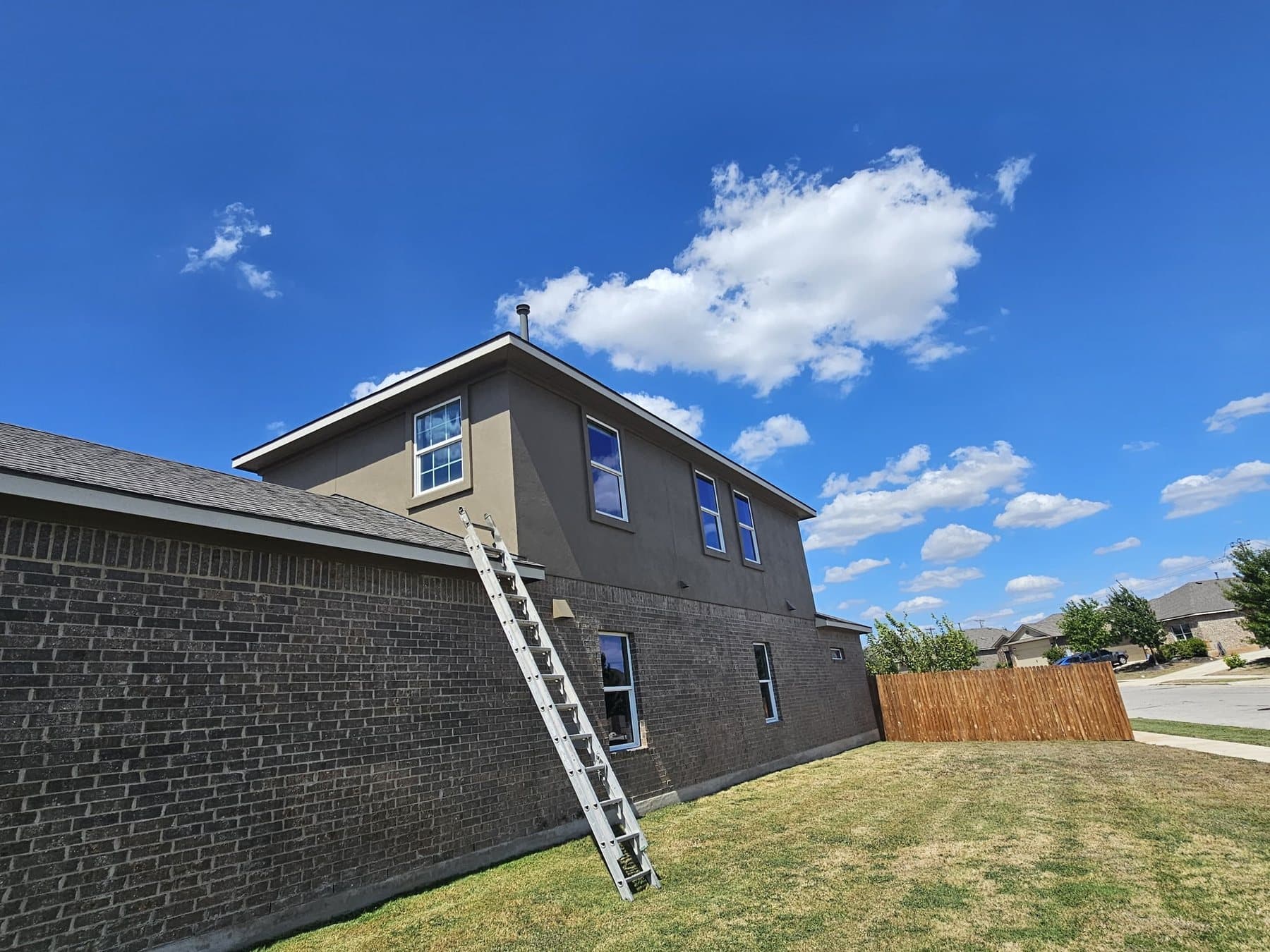 Two-storey Greater Austin home exterior with a ladder set for painting work
