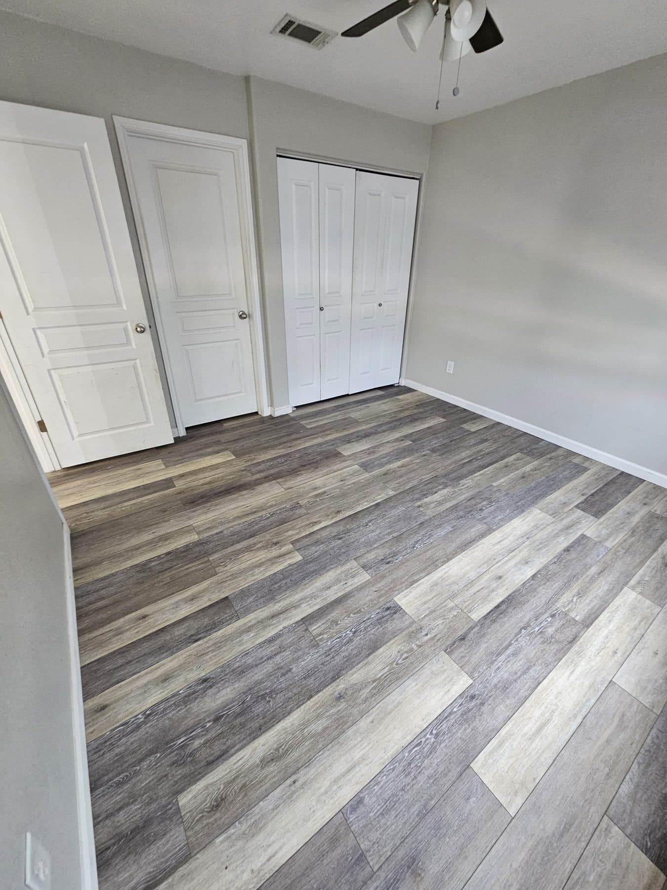 Finished luxury vinyl plank flooring running wall to wall in a bedroom